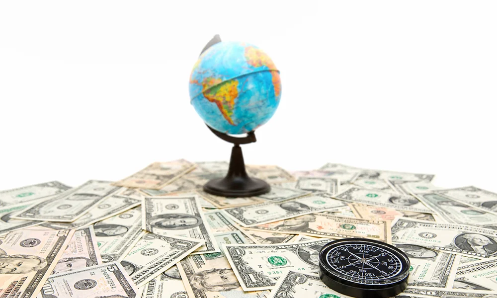 Globe, US dollar notes, and compass representing exchange-rate volatility and global business strategy